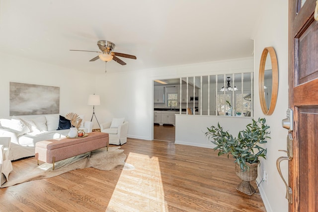 living area with ceiling fan, baseboards, and wood finished floors