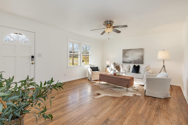 living area featuring wood finished floors, a ceiling fan, and baseboards