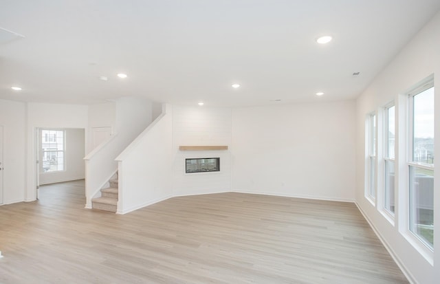 spare room featuring plenty of natural light, a fireplace, recessed lighting, and light wood finished floors