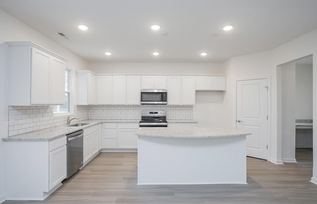 kitchen featuring visible vents, light wood-style flooring, a sink, stainless steel appliances, and white cabinets