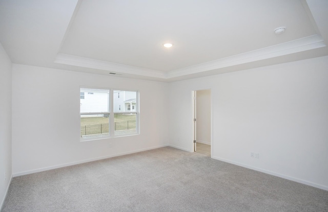 empty room featuring baseboards, recessed lighting, crown molding, a raised ceiling, and light colored carpet