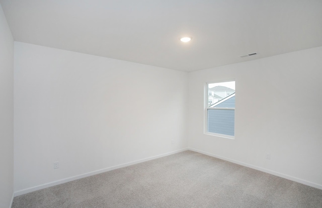 spare room with recessed lighting, baseboards, light carpet, and visible vents