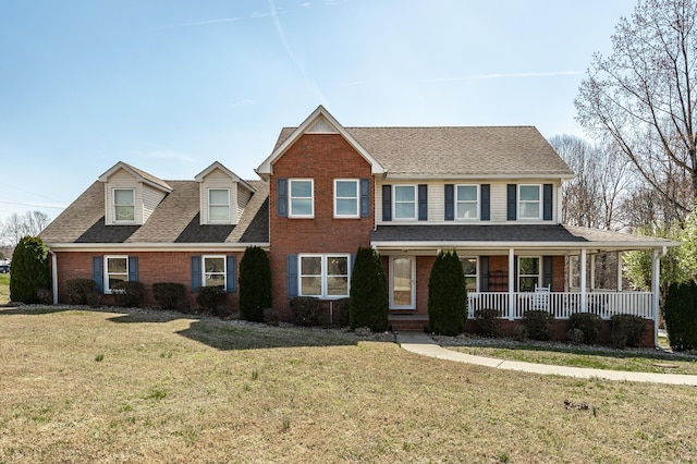 view of front facade with a shingled roof, a front yard, a porch, and brick siding