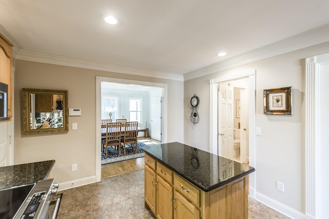 kitchen with baseboards, stainless steel electric range, a center island, dark stone countertops, and crown molding