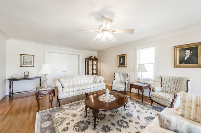 living area featuring baseboards, a ceiling fan, wood finished floors, and ornamental molding