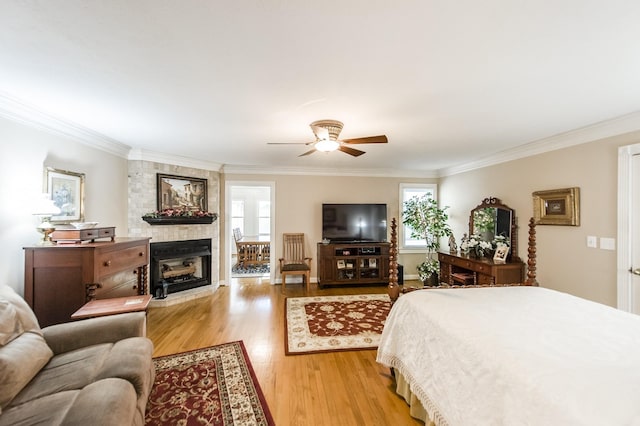 bedroom with ornamental molding, a large fireplace, multiple windows, and light wood-style flooring