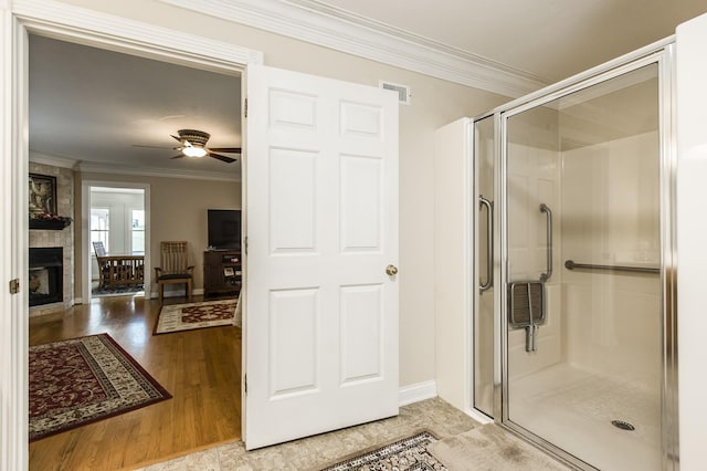 full bathroom with a large fireplace, wood finished floors, visible vents, ornamental molding, and a stall shower