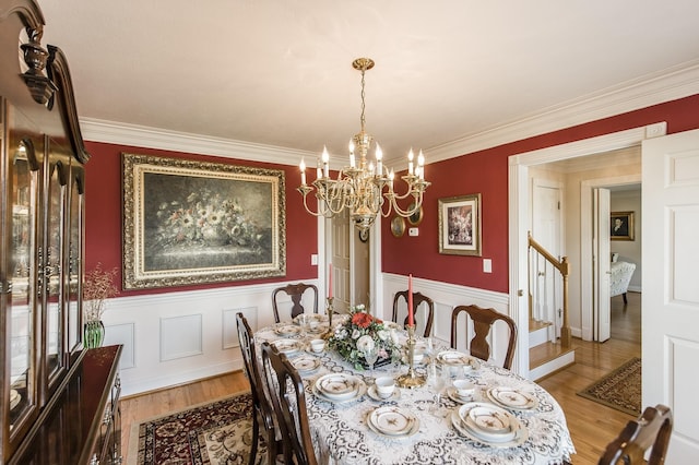 dining area featuring a wainscoted wall, light wood-style flooring, stairway, and a chandelier