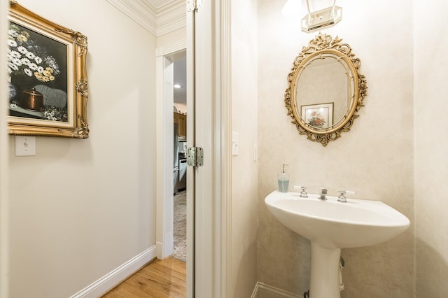 bathroom with ornamental molding, baseboards, and wood finished floors