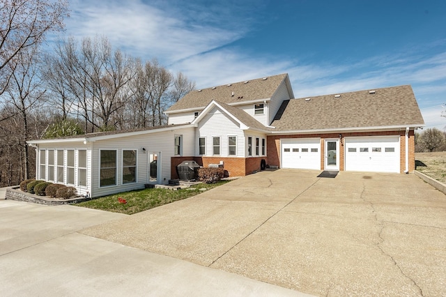 view of front facade with a shingled roof, concrete driveway, brick siding, and an attached garage