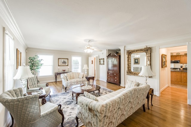 living room featuring baseboards, crown molding, light wood finished floors, and ceiling fan