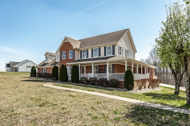 view of front facade with covered porch, brick siding, and a front yard