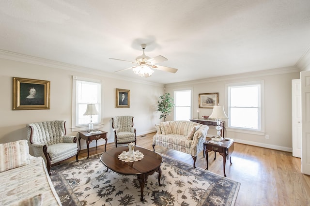 living area with light wood finished floors, ceiling fan, baseboards, and crown molding