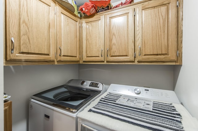 clothes washing area with washing machine and dryer and cabinet space