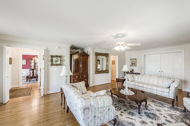 living room featuring crown molding, ceiling fan, light wood-style flooring, and baseboards