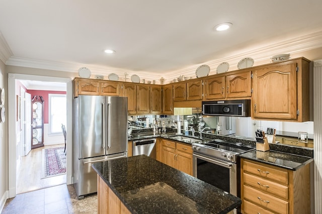 kitchen featuring a kitchen island, appliances with stainless steel finishes, brown cabinets, dark stone countertops, and crown molding