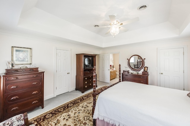 bedroom with light colored carpet, a raised ceiling, visible vents, and ensuite bathroom