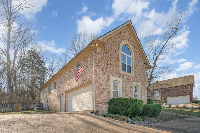 view of home's exterior with brick siding, driveway, fence, and central air condition unit