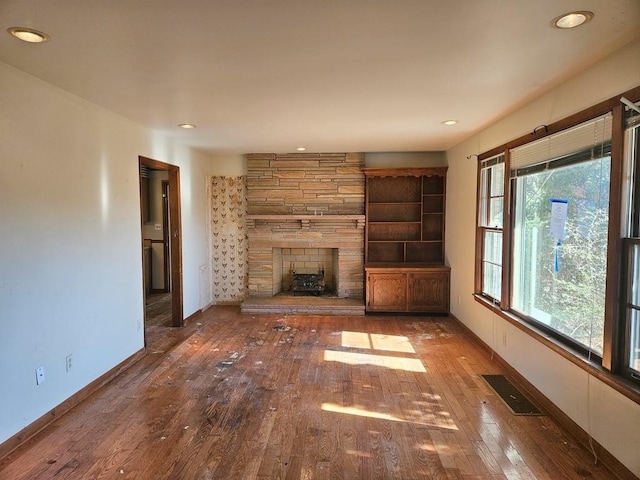 unfurnished living room featuring hardwood / wood-style flooring, baseboards, a fireplace, and visible vents