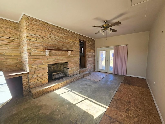 unfurnished living room with french doors, a stone fireplace, a ceiling fan, and baseboards