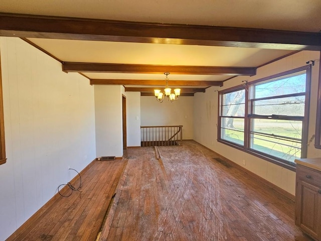 empty room with visible vents, beam ceiling, a chandelier, and hardwood / wood-style floors