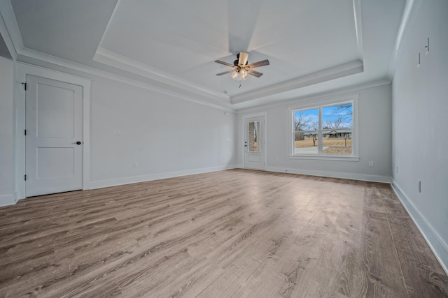 spare room featuring a tray ceiling, wood finished floors, and baseboards