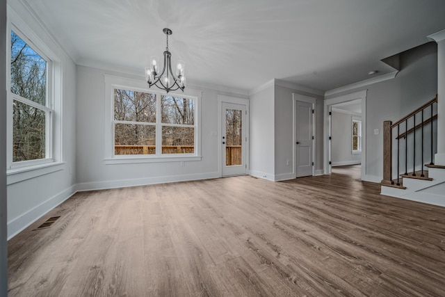 unfurnished dining area with visible vents, ornamental molding, wood finished floors, stairs, and a chandelier