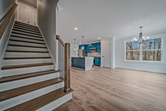 staircase featuring arched walkways, baseboards, wood finished floors, and a notable chandelier