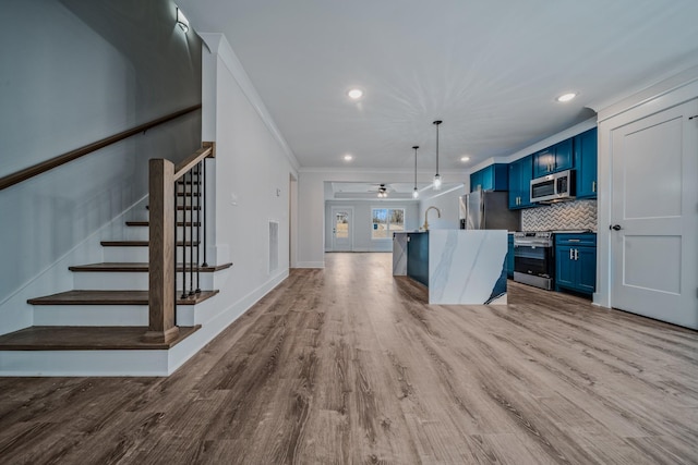 kitchen featuring blue cabinetry, tasteful backsplash, appliances with stainless steel finishes, ornamental molding, and wood finished floors