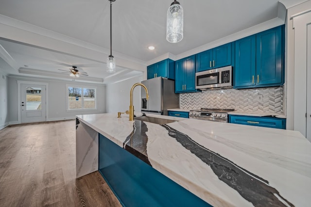 kitchen featuring blue cabinetry, stainless steel appliances, decorative backsplash, a sink, and wood finished floors