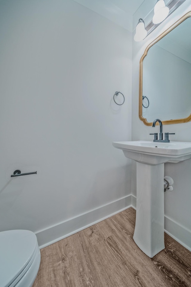 bathroom with wood finished floors, toilet, and baseboards