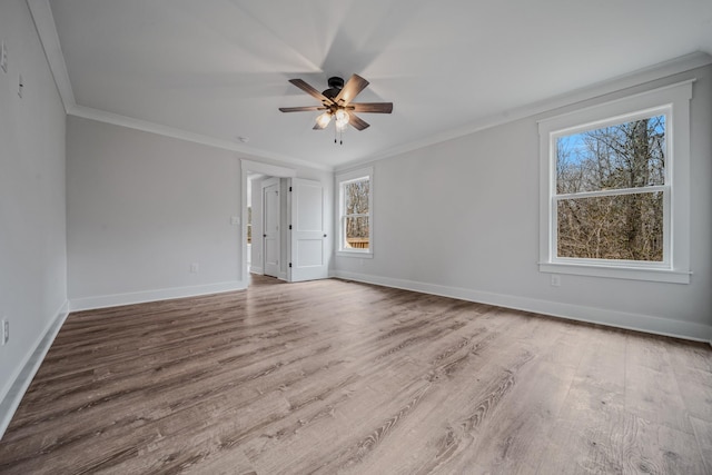 empty room with ornamental molding, a ceiling fan, baseboards, and wood finished floors