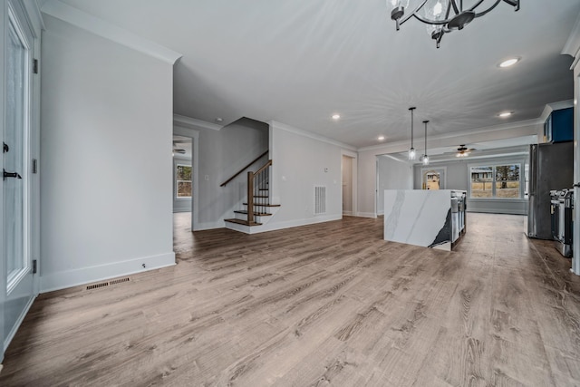 unfurnished living room with wood finished floors, visible vents, baseboards, stairs, and crown molding