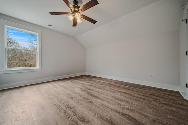 bonus room with lofted ceiling, wood finished floors, a ceiling fan, visible vents, and baseboards