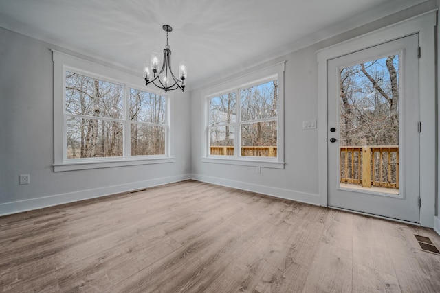 unfurnished dining area featuring a chandelier, wood finished floors, visible vents, and baseboards