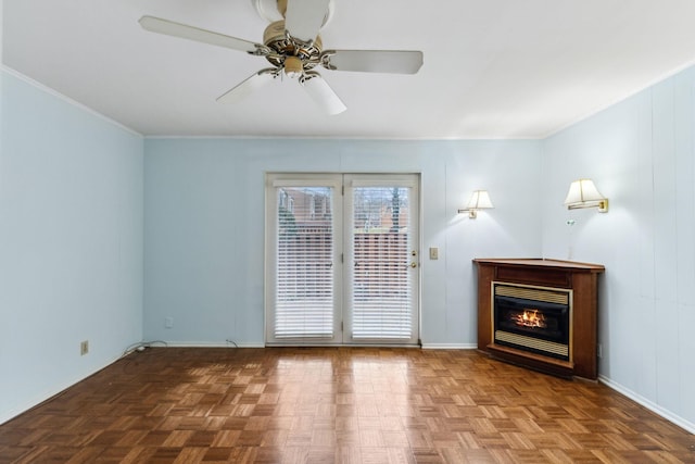 interior space featuring ceiling fan, baseboards, a glass covered fireplace, and crown molding