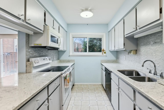 kitchen with light tile patterned floors, decorative backsplash, a sink, white appliances, and baseboards