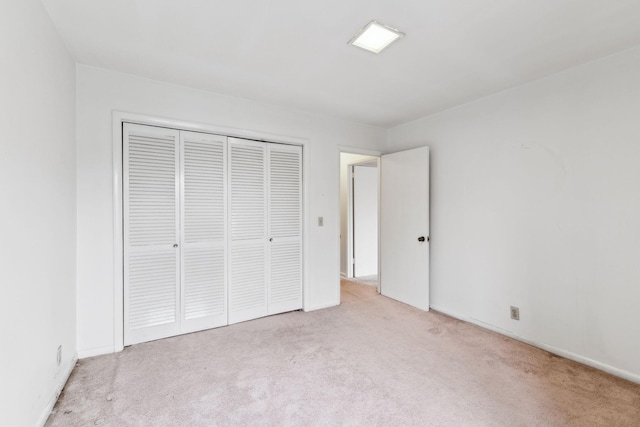 unfurnished bedroom featuring a closet and light carpet