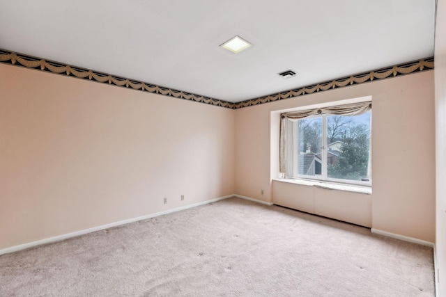 spare room with baseboards, visible vents, and light colored carpet