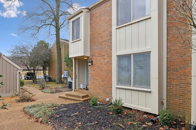 view of home's exterior with entry steps, board and batten siding, and brick siding