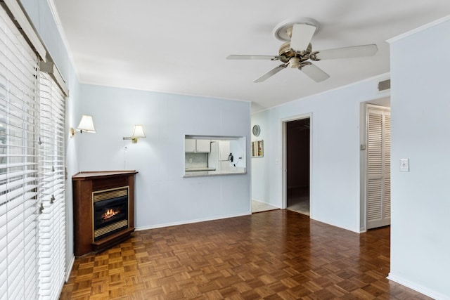 unfurnished living room featuring baseboards, visible vents, a ceiling fan, a glass covered fireplace, and crown molding