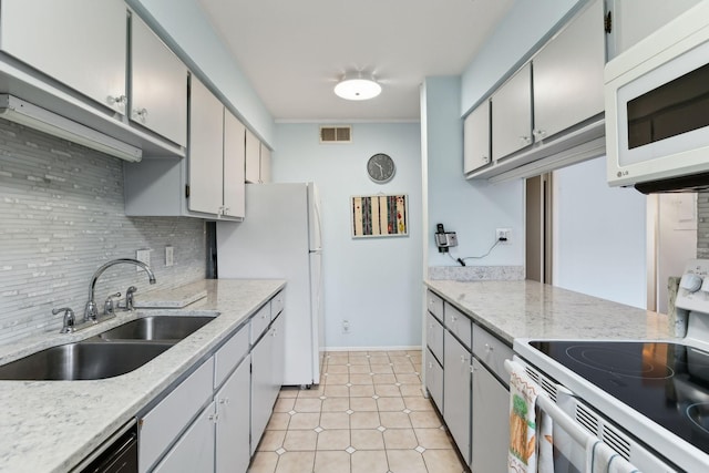 kitchen with light tile patterned floors, visible vents, backsplash, a sink, and white appliances