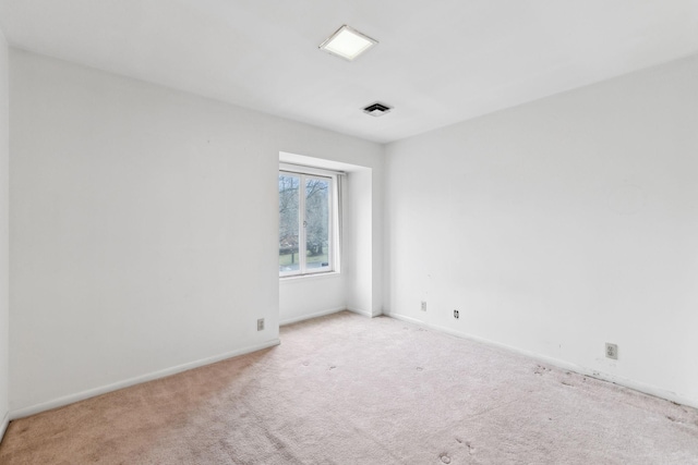 carpeted spare room featuring visible vents and baseboards