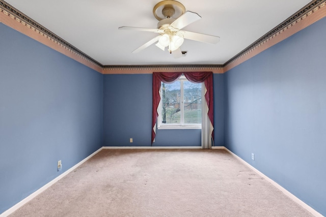 carpeted empty room with ceiling fan, crown molding, and baseboards