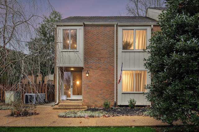 view of front of home featuring brick siding and fence