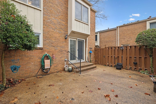 exterior space with entry steps, a patio area, brick siding, and fence