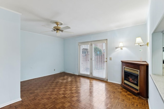 unfurnished living room featuring a ceiling fan, a glass covered fireplace, crown molding, and baseboards