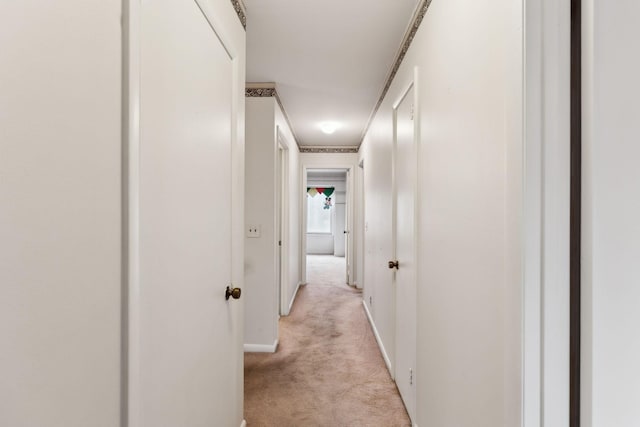 hallway featuring light carpet and baseboards