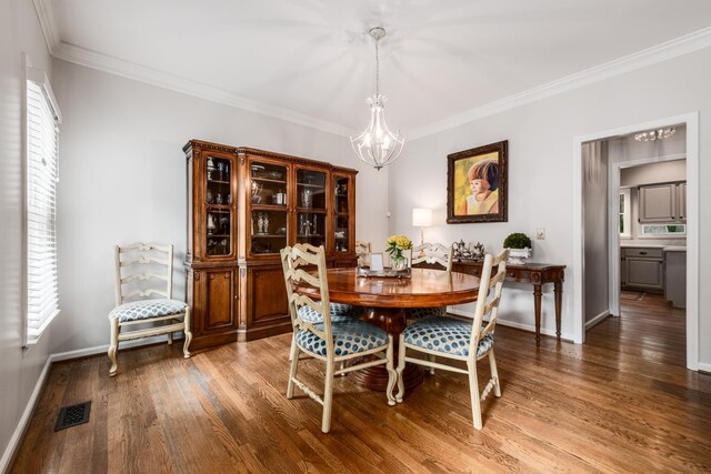 dining area featuring a chandelier, wood finished floors, visible vents, and crown molding