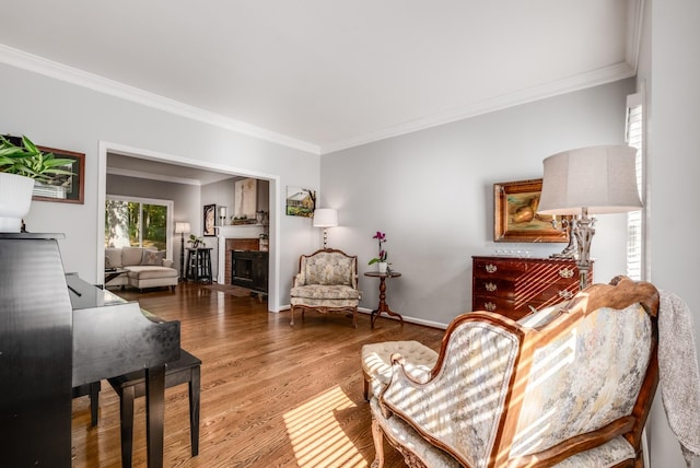 sitting room featuring ornamental molding, a fireplace, wood finished floors, and baseboards